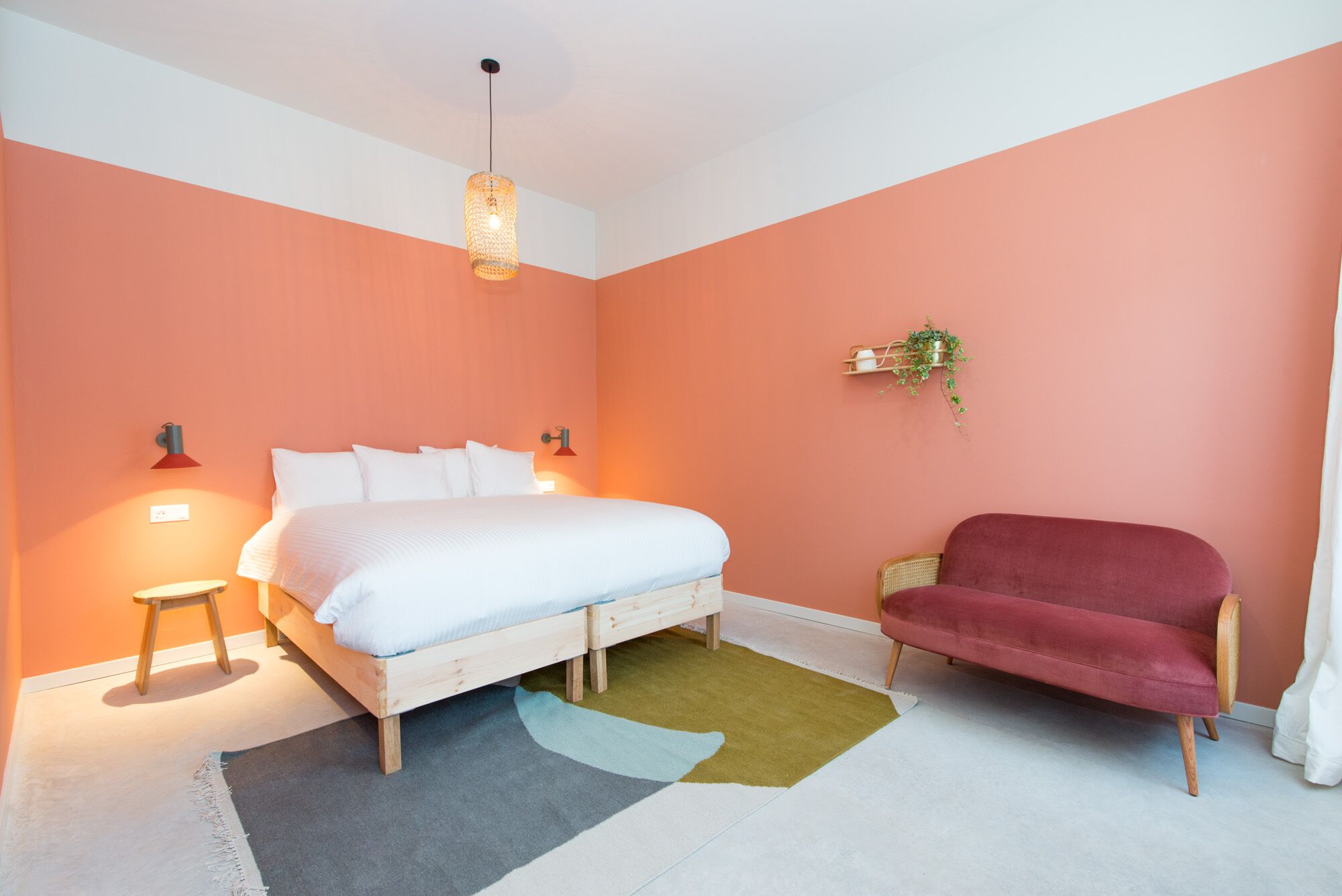 A bedroom with a bed, bedside lamps, a red sofa, and a small table.