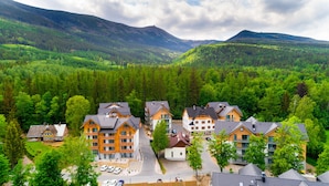 Un chalet de montagne composé de plusieurs bâtiments, entouré d’une forêt dense et de montagnes.