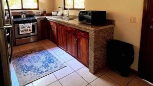 Una cocina con armarios de madera, piso de baldosas y ventana con vista a espacios verdes.