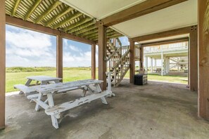 A covered picnic area with picnic tables and a staircase leading to an upper level. - Mermaid Manor - Beachfront, Sun, Sand, Good Times! (Surfside Beach)