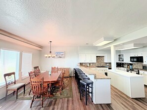 Cozinha espaçosa com ilha central, armários brancos e área de jantar com mesa e cadeiras de madeira.
