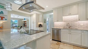 A modern kitchen with white cabinetry, a stainless steel dishwasher, and a marble countertop.