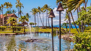 A resort pool with a water fountain, surrounded by palm trees and a clear blue sky. - OCEAN and POOL View, remodeled 2 bdrm condo with A/C - PAPAKEA K406 (Lahaina)