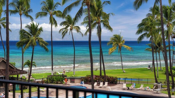 A poolside view with palm trees, a clear sky, and a view of the ocean. - OCEAN and POOL View, remodeled 2 bdrm condo with A/C - PAPAKEA K406 (Lahaina)