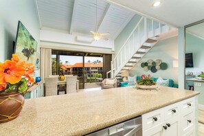 A modern kitchen with a granite countertop, a built-in dishwasher, and a view of the outdoor patio.