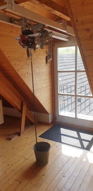 Cozy loft-style room with a sloped ceiling, wooden floor, and a large window offering a view of the exterior staircase.