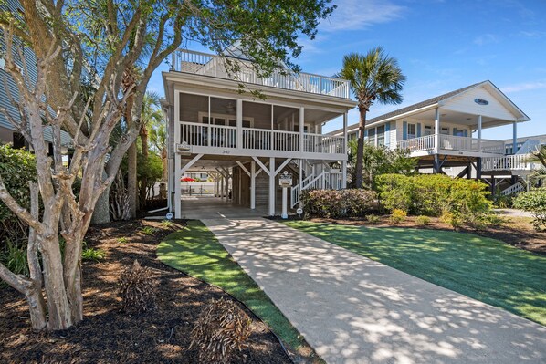 A two-story house with a balcony, a covered porch, and a well-maintained lawn.