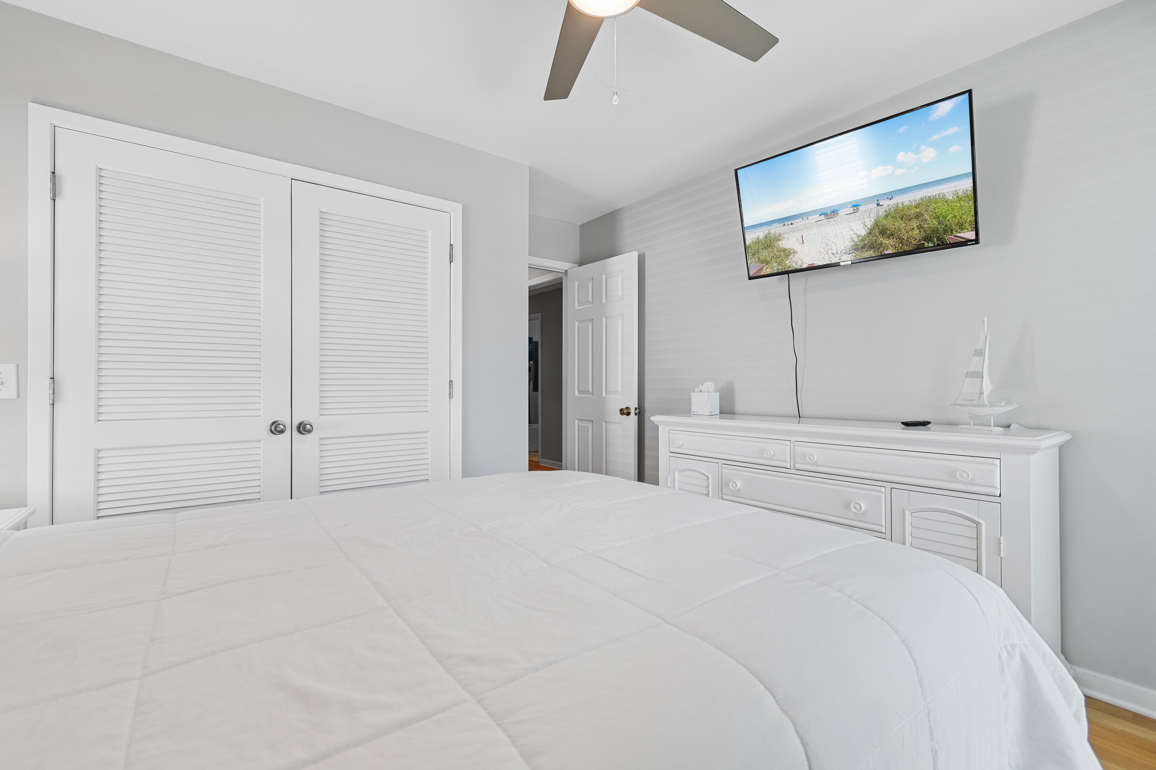 Ein Schlafzimmer mit einem großen Bett, einem an der Wand montierten Fernseher und einer Kommode.