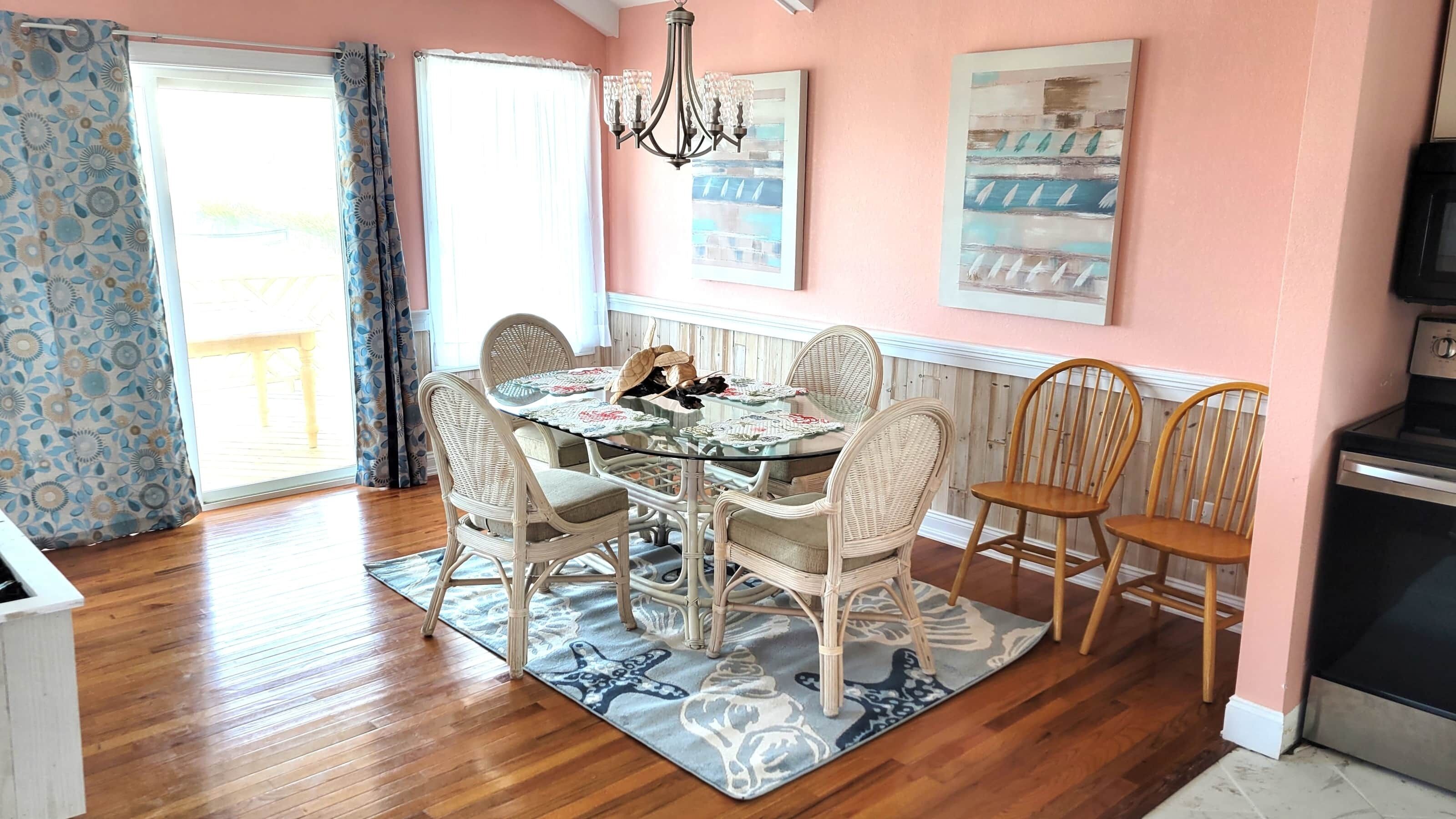 Un coin repas avec une table en verre, des chaises en osier et un tapis à motifs.