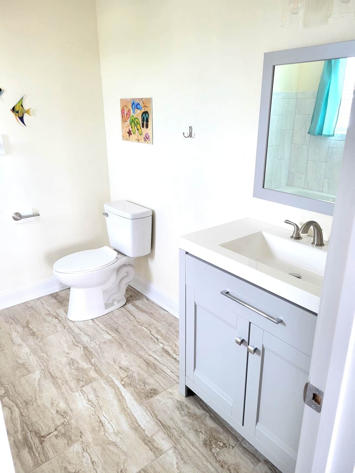 A bathroom with a toilet, a sink, and a mirror.