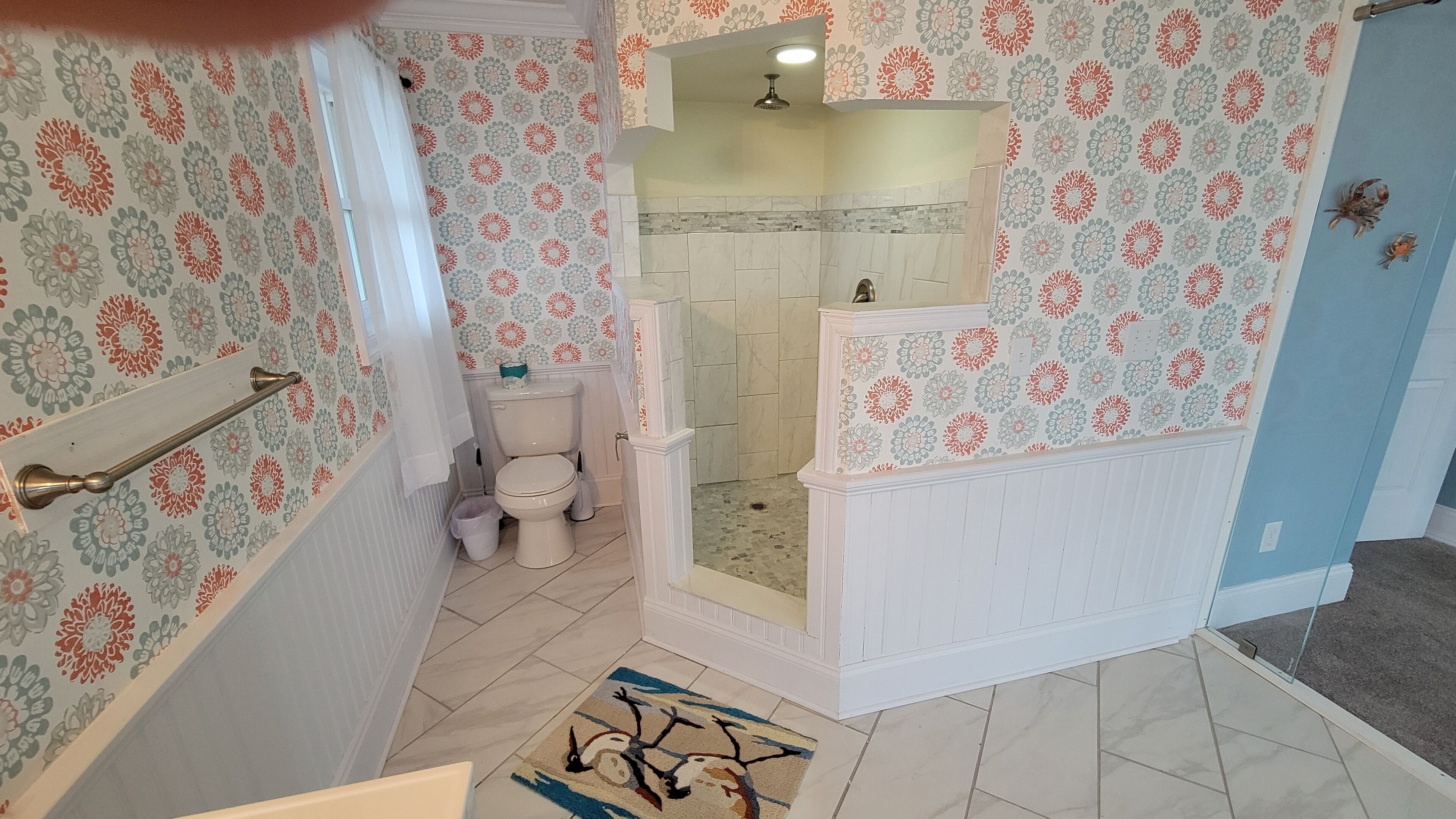 A bathroom with a shower, toilet, and a patterned wall.