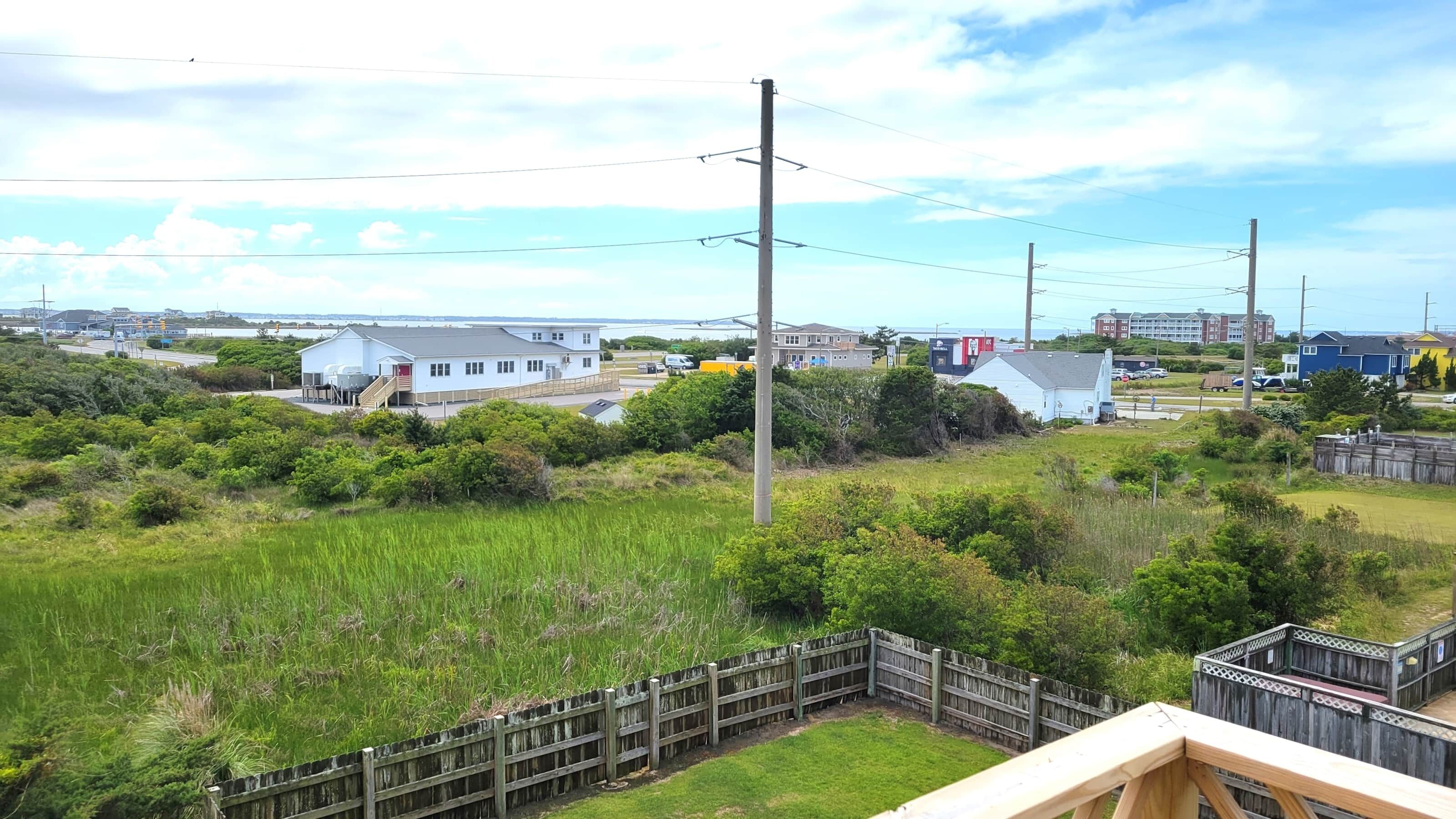 A coastal residential area with houses, a dock, and a grassy field.