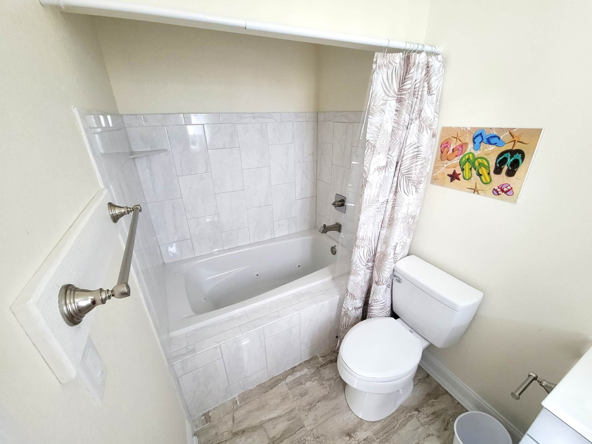 Et badeværelse med badekar, toilet og bruseforhæng.