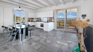 A modern kitchen with a large island, white cabinetry, and a dining area with a glass table and chairs.