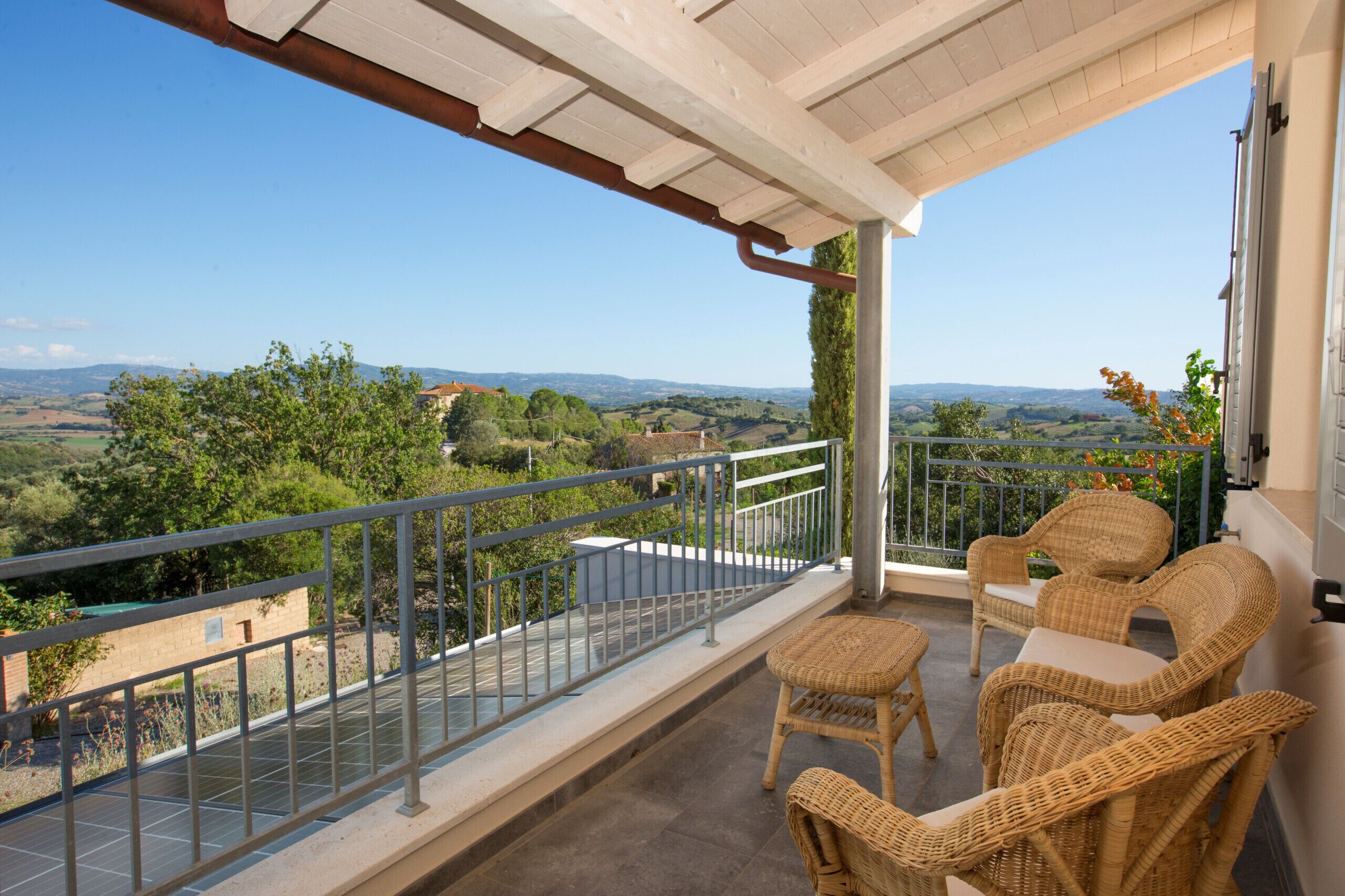 Un balcon doté de meubles en osier et offrant une vue sur la campagne.