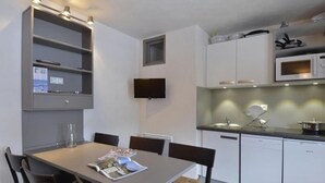A modern kitchen with white cabinets, a built-in microwave, and a dining area with a table and chairs. - 100m from resort center, 3rd floor, view ski slopes, swimming pool, balcony, tv, ski locker, 35m² (La Plagne)