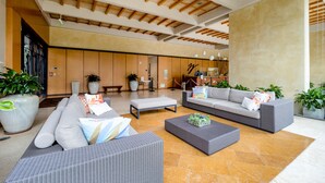 Eine geräumige Lobby mit modernen Möbeln, darunter Sofas und ein Couchtisch, sowie eine große Pflanze in einem Topf.
