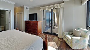 Ein Hotelzimmer mit Bett, Schminktisch, Fernseher, einem Balkon mit Aussicht und einem Sessel.