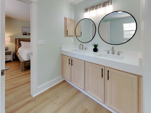 A bathroom with a double sink, two round mirrors, and wooden cabinets.