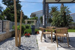 Un'area patio esterna con pavimento in pietra, mobili in vimini e una struttura a pergola.