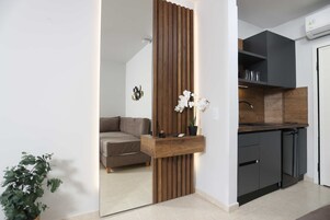 Una cocina moderna con armarios oscuros, un revestimiento de pared de madera y una orquídea en maceta.