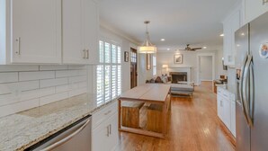Una cocina amplia con armarios blancos, una isla de madera y un refrigerador empotrado.