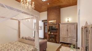 A bedroom with a four-poster bed, a fireplace, wooden cabinets, and a chandelier. - W15 Lake Gergory (Nuwara Eliya)
