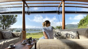 A person sitting on a sofa with a view of a lake and hills. - W15 Lake Gergory (Nuwara Eliya)