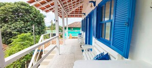 A balcony with a view of a green building, white railings, and a blue awning. - Pousada Costa Verde (Angra dos Reis)