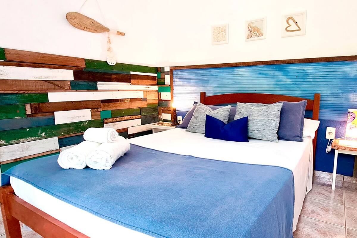 A bed with a blue bedspread, pillows, and a wooden headboard.