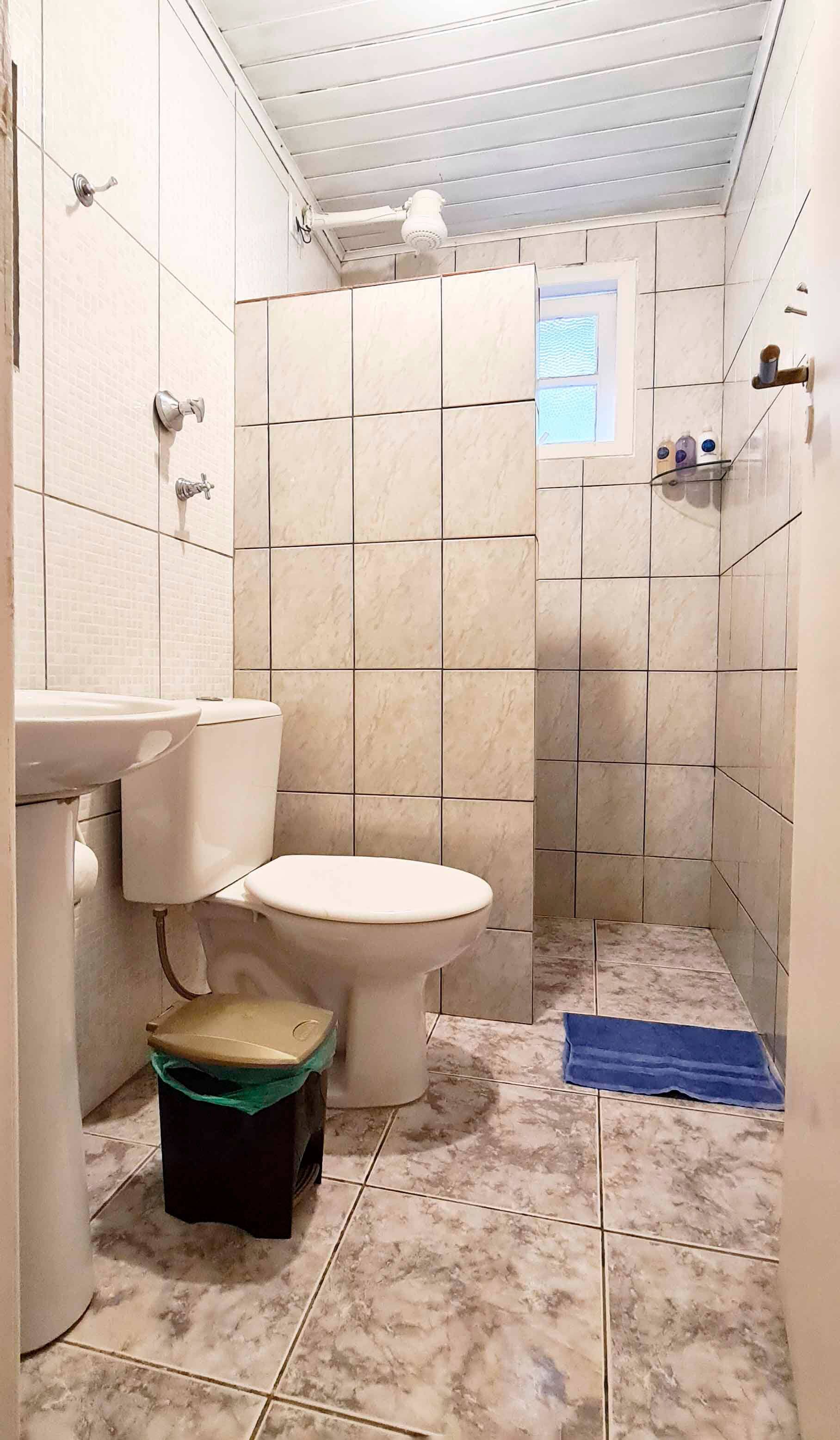 Un baño pequeño con inodoro, lavamanos y ducha.