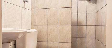 Un baño pequeño con inodoro, lavamanos y ducha.
