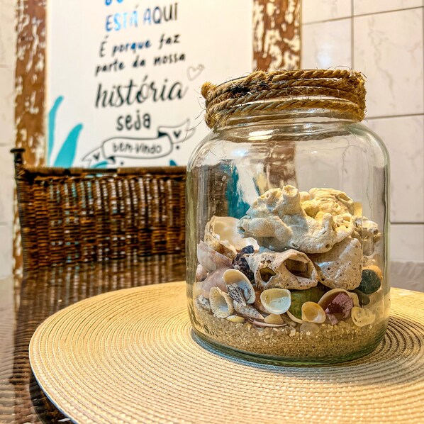 A glass jar filled with seashells on a woven placemat. - Pousada Costa Verde (Angra dos Reis)