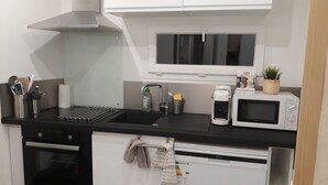 Eine kleine Küche mit schwarzem Arbeitsplatz, einer Edelstahl-Spüle, einer Mikrowelle, einer Kaffeemaschine und einem kleinen Kühlschrank.