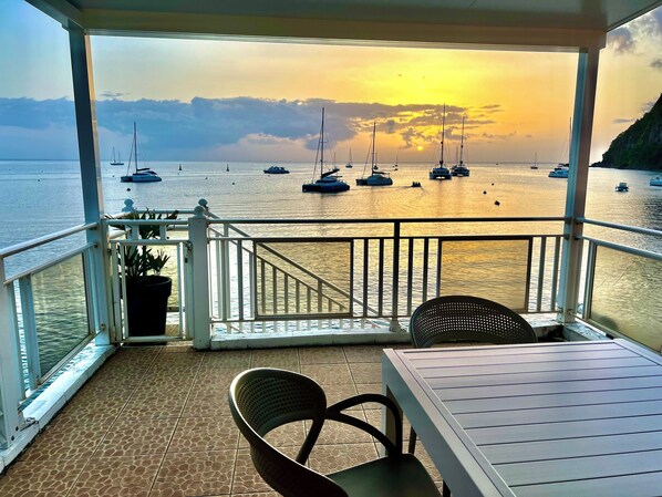 Un balcon avec vue sur la mer, les bateaux et le coucher du soleil.