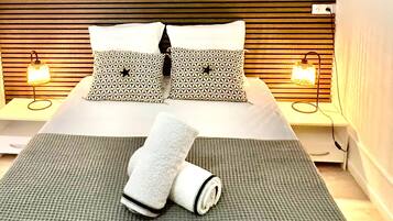 A hotel room with a bed, two bedside lamps, a painting, and a window.