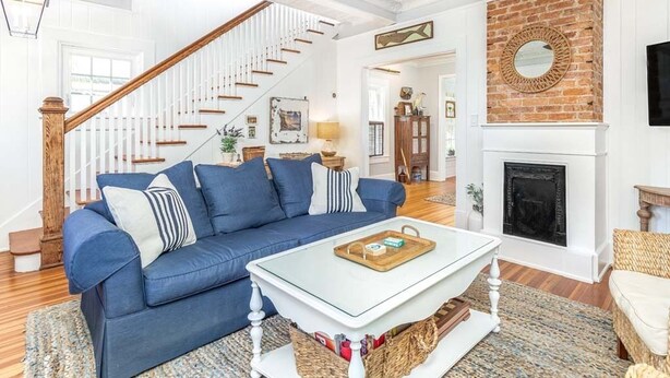 Una sala de estar con un sofá azul, una mesa de centro blanca y una chimenea.