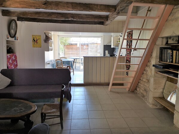 Un salon chaleureux avec un canapé, une petite table, une échelle et une bibliothèque.