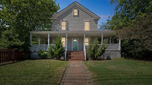 A two-story house with a covered front porch and a front door. - Captains Quarters By The Bay 3 Bedroom Cottage by RedAwning (Norfolk)