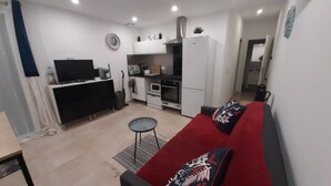 A compact living space with a kitchenette, a sofa, a small table, and a TV. - Happy Home for You Lunel: Happiness at the end of the journey. (Lunel)