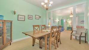 A dining area with a wooden table and chairs, a chandelier, and framed pictures on the walls. - Manor And Mutts #1 4 Bedroom Cottage by RedAwning (Norfolk)