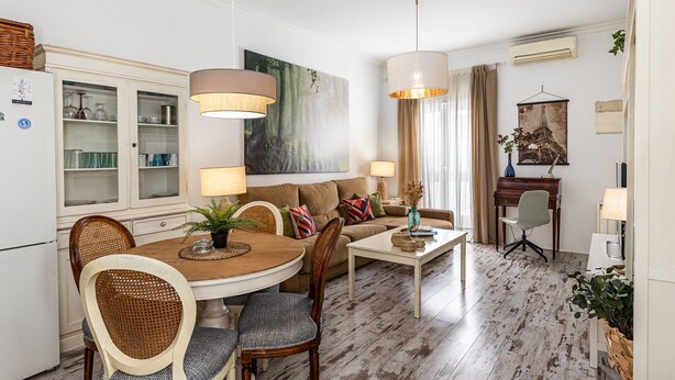 Een moderne woonkamer met een eethoek, met een ronde tafel, banken en een groot schilderij.