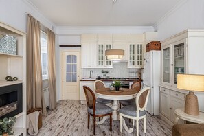 A compact kitchen with white cabinetry, a round dining table, and a central island.