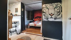 A bedroom with a large tiger mural, a wooden head sculpture, and a bed with a red and white patterned bedspread. - Very nice T1bis in Biarritz Bibi (Biarritz)
