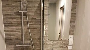 A modern bathroom with a glass-enclosed shower, a white sink, and a dark wooden cabinet. - Very nice T1bis in Biarritz Bibi (Biarritz)