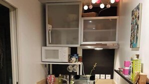 A compact kitchen with a microwave, sink, and a small dining area with a chair. - Very nice T1bis in Biarritz Bibi (Biarritz)