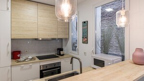 Une cuisine moderne avec des meubles en bois, un évier en acier inoxydable, un four à micro-ondes et des luminaires suspendus.