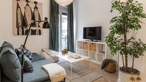 Un salon moderne avec un canapé, une table basse, un téléviseur, une lampe et une plante en pot.