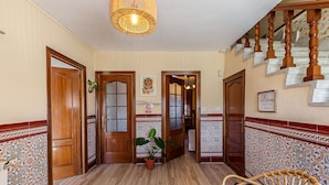 Un corridoio con pareti in piastrelle decorate, porte in legno e una scala.