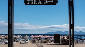 A wooden pathway leading to FILA Beach with beach umbrellas and lounge chairs visible in the background. - FİLA OTEL AYVALIK (Ayvalik)